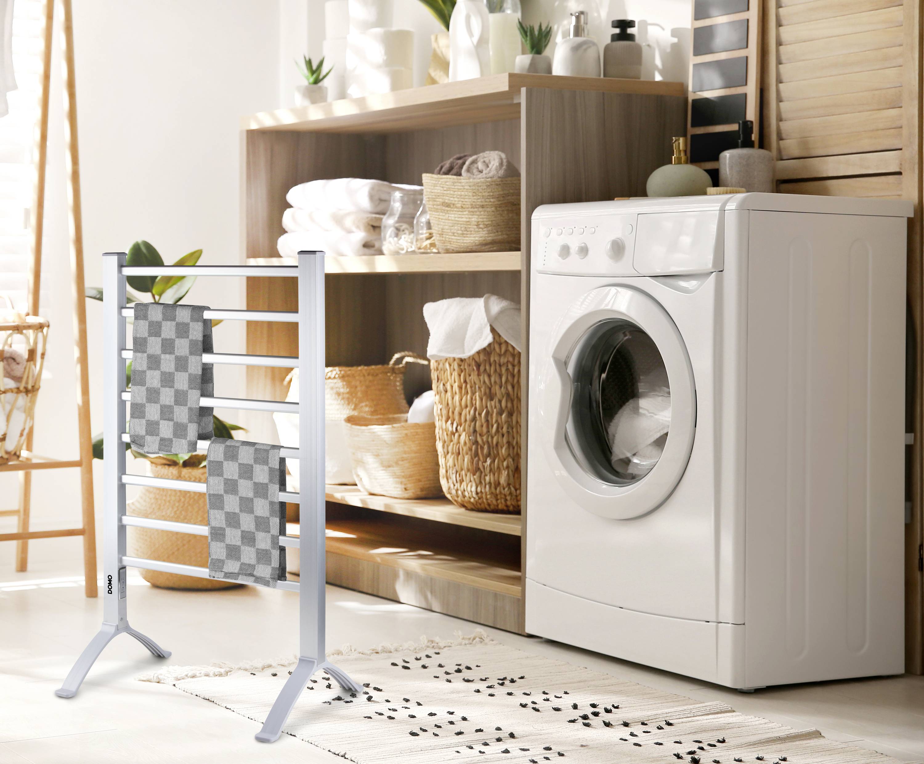 Waschküche mit Waschmaschine, Regal mit Handtüchern und Korb. Ein Wäscheständer mit Handtüchern steht im Vordergrund.