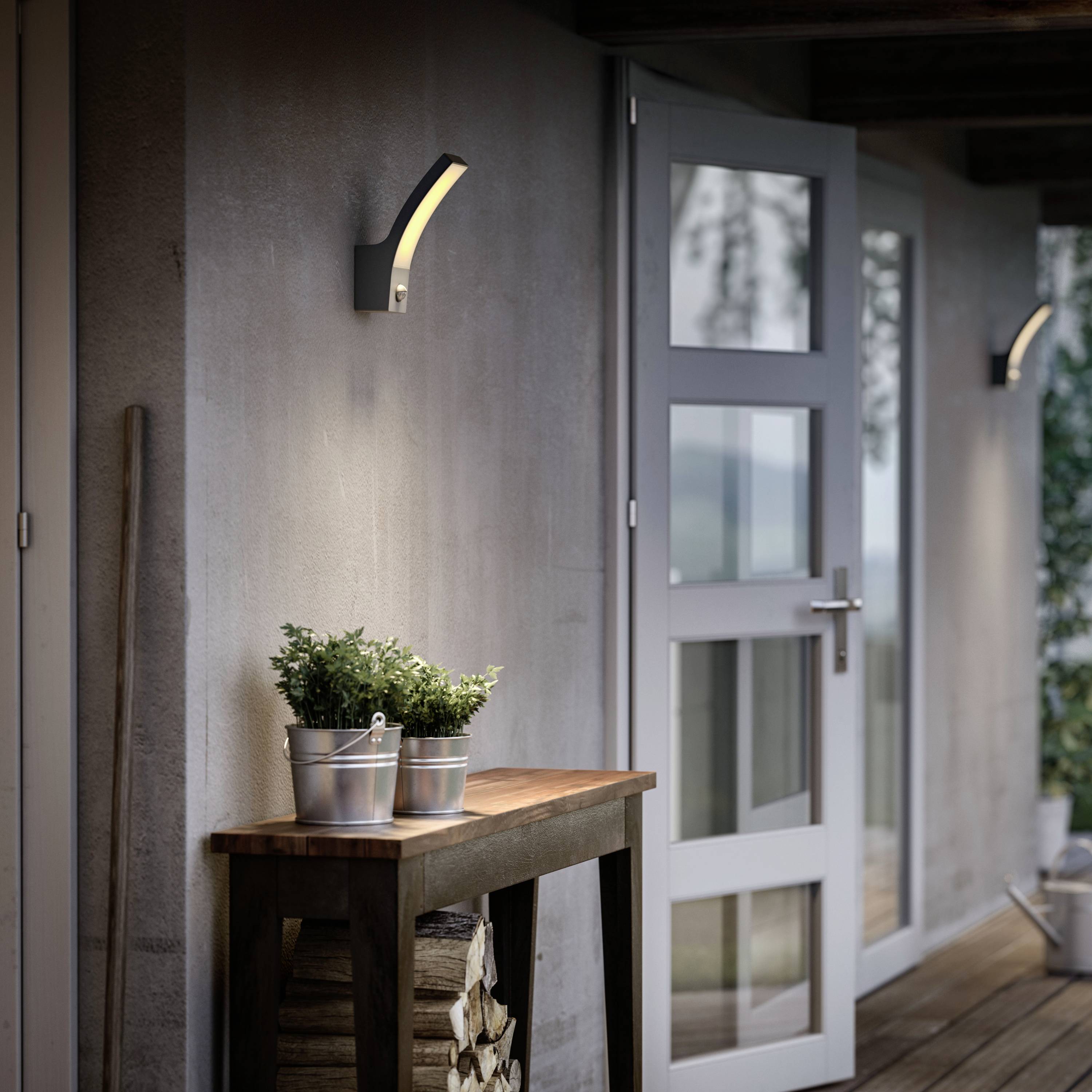 Ein hölzernes Seitenbord mit Metalltopf und Pflanzen steht auf einer Terrasse. An der Wand sind moderne Außenlampen montiert.