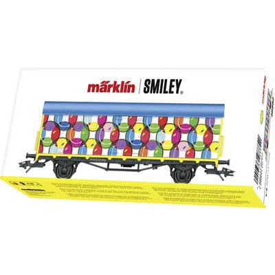 Ein bunter Modellgüterwagen mit fröhlichen Smileys und einem blauen Dach in einer Verpackung mit der Aufschrift 'märklin SMILEY'.
