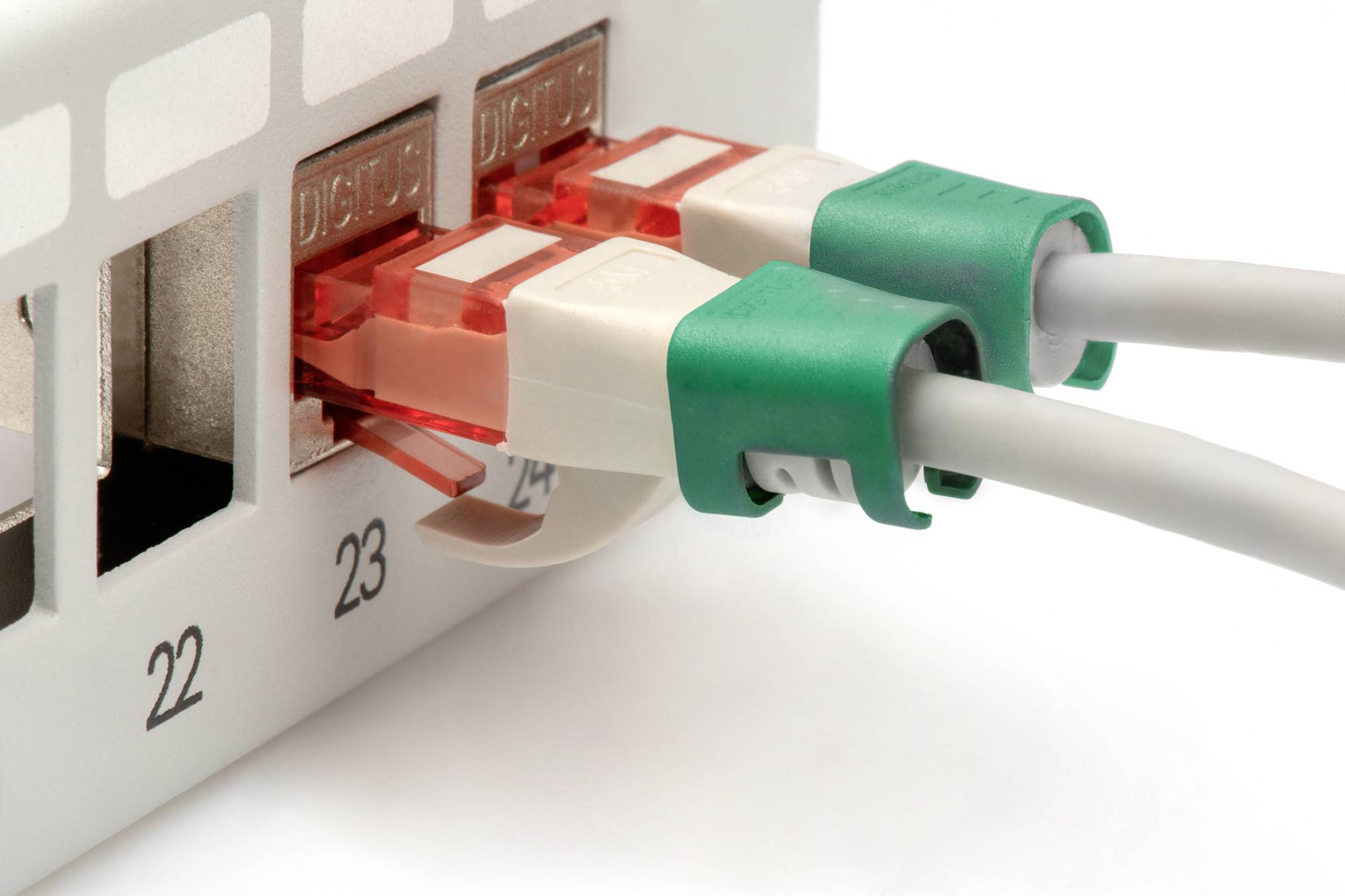 Zwei grüne Netzwerkkabel sind in Anschlüsse eines weißen Netzwerkgeräts eingesteckt.