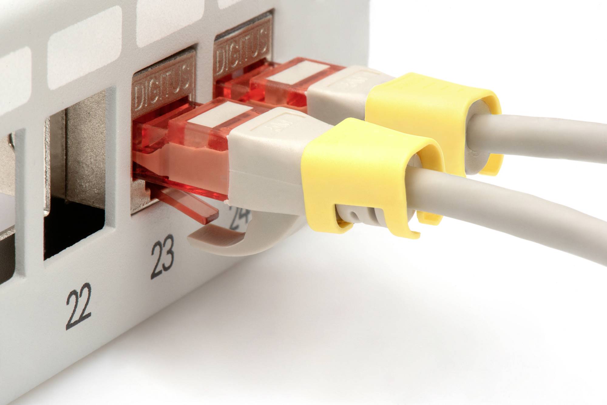 Zwei Netzwerkkabel mit gelben Steckern sind in die Anschlüsse 23 und 24 eines Schaltdosenfelds eingesteckt.