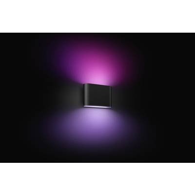 Schwarze Wandlampe vor dunklem Hintergrund, strahlt violettes und pinkes Licht nach oben und unten aus.