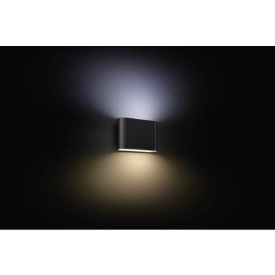 Wandleuchte leuchtet nach oben und unten, erzeugt weiches, diffuses Licht auf einer dunklen Wand. Minimalistisches Design.
