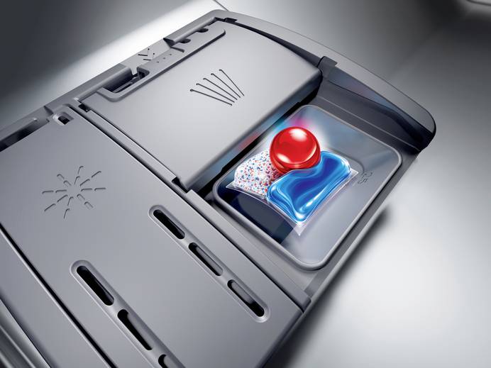 Das Bild zeigt, in welches Fach in der Spülmaschine ein Reinigungstab gehört. Dabei ist nur die Innenseite der Tür zu sehen und die Kamera recht nah an die Fächer herangezoomt.