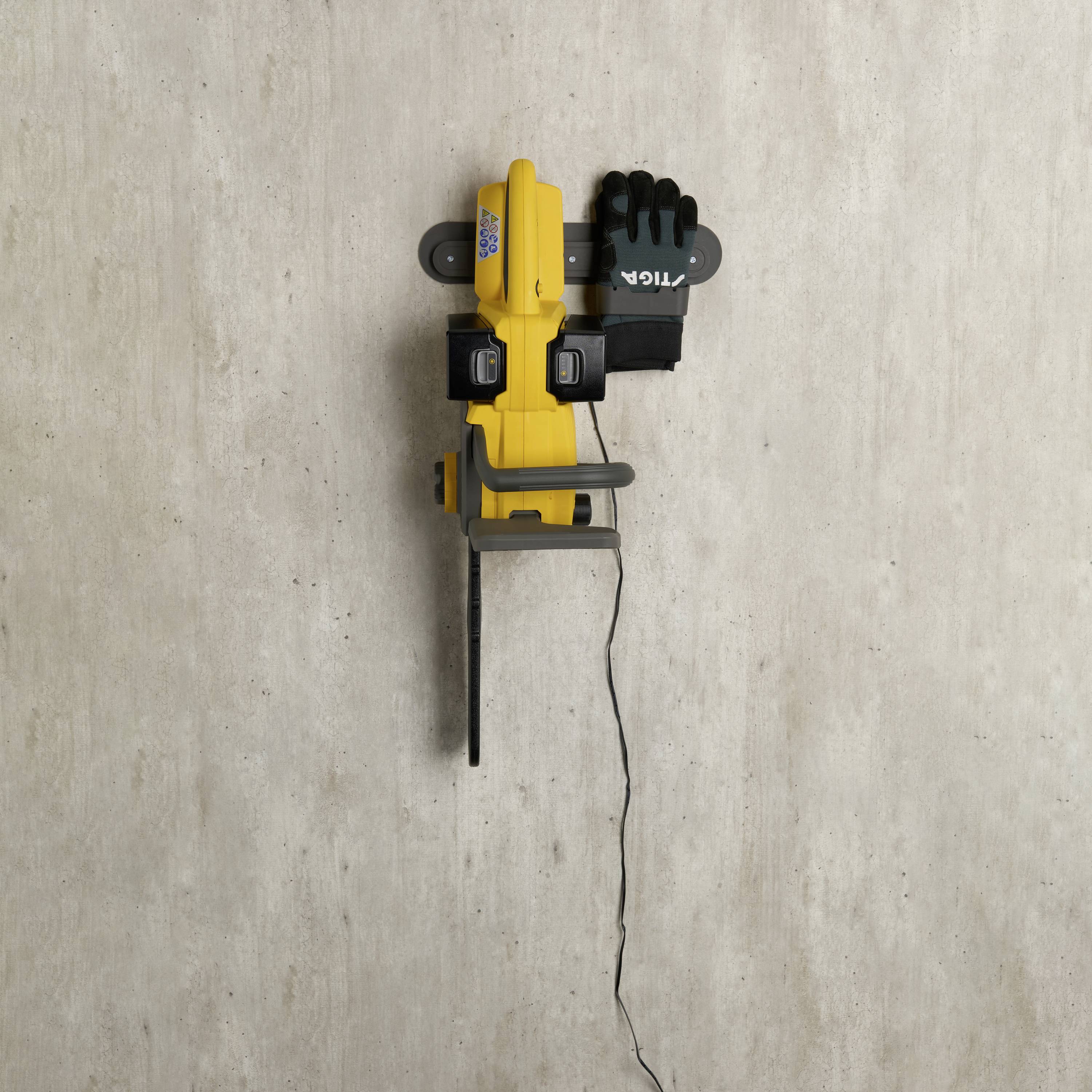 Eine gelbe Klettermauerhalterung mit abgenutztem dunkelgrauen Handschuh, montiert auf einer Betonwand. Ein Kabel hängt lose herab.