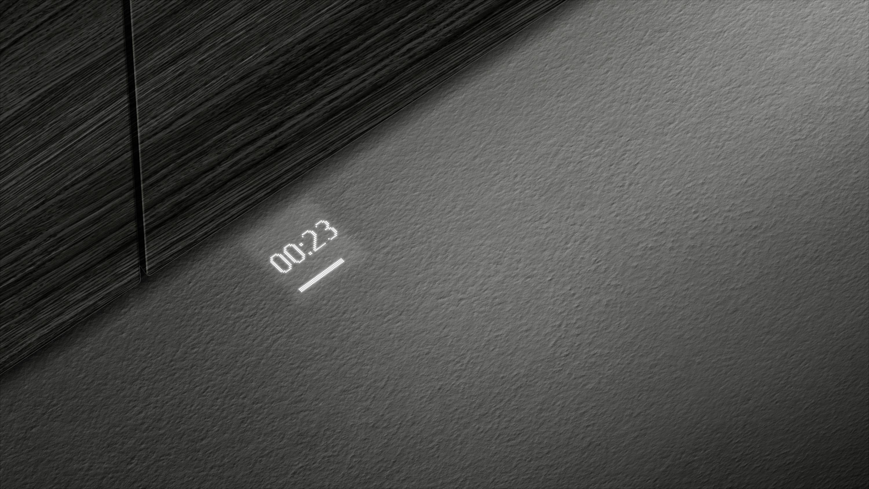 Eine digitale Anzeige projiziert '00:23' auf eine Wand unter einem horizontalen Holzbrett. Kein weiterer Kontext vorhanden.