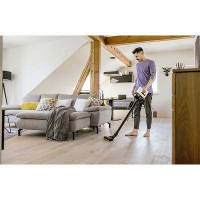 Eine Person saugt ein modernes Wohnzimmer mit einem kabellosen Staubsauger. Die Einrichtung ist hell und gemütlich.