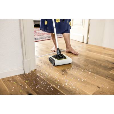 Eine Person reinigt einen Holzboden mit einem elektrischen Bodenwischer; Konfetti wird unter dem Wischer aufgesaugt.
