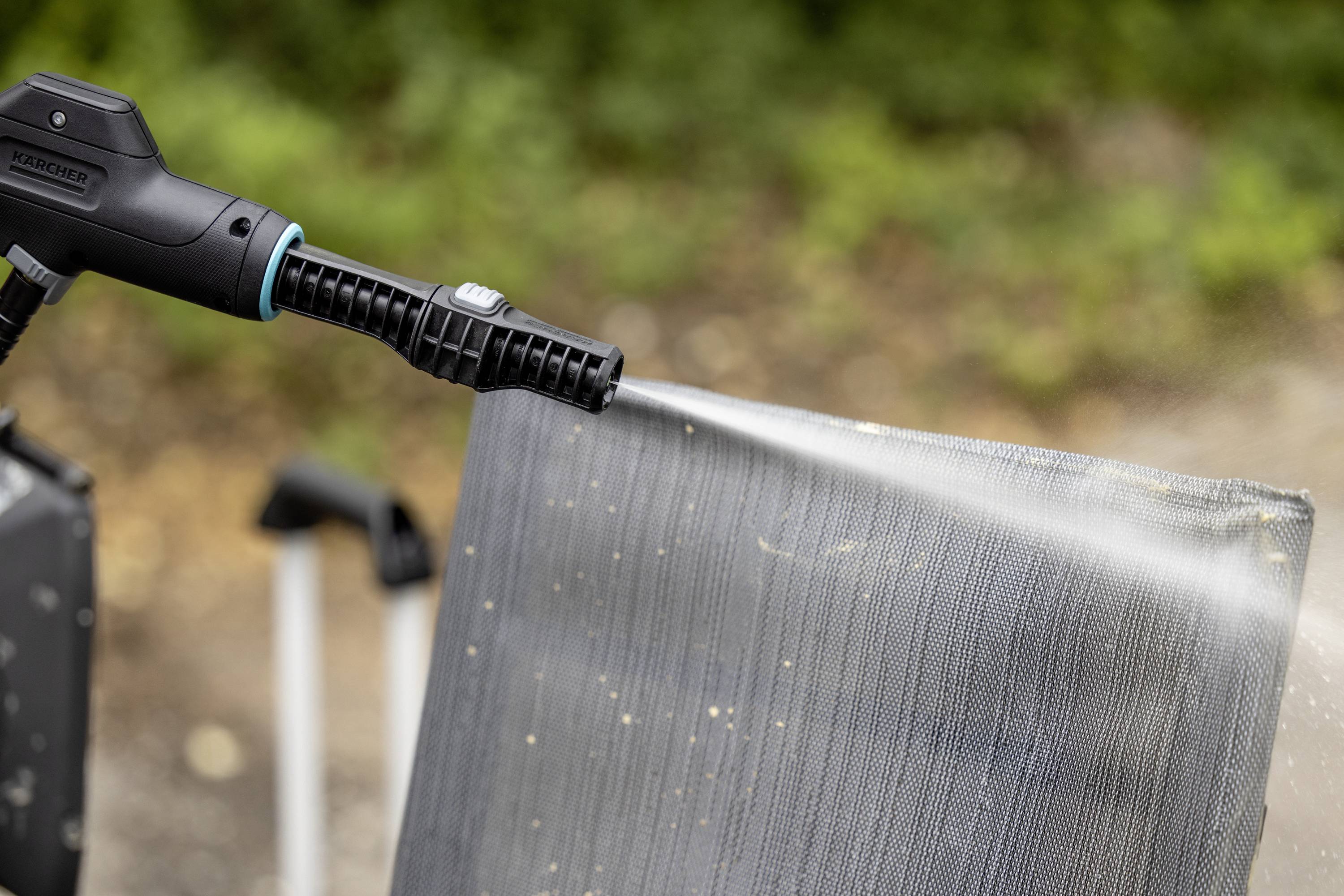 Ein Hochdruckreiniger spritzt Wasser auf eine schmutzige Oberfläche im Freien, um sie zu reinigen.