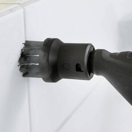 Eine elektrische Reinigungsbürste reinigt die Fugen zwischen weißen Fliesen. Die Bürste hat schwarze Borsten.
