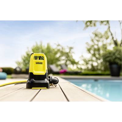 Gelber Hochdruckreiniger auf Holzdeck am Pool, Hintergrund unscharf mit grünen Bäumen und blauem Himmel.