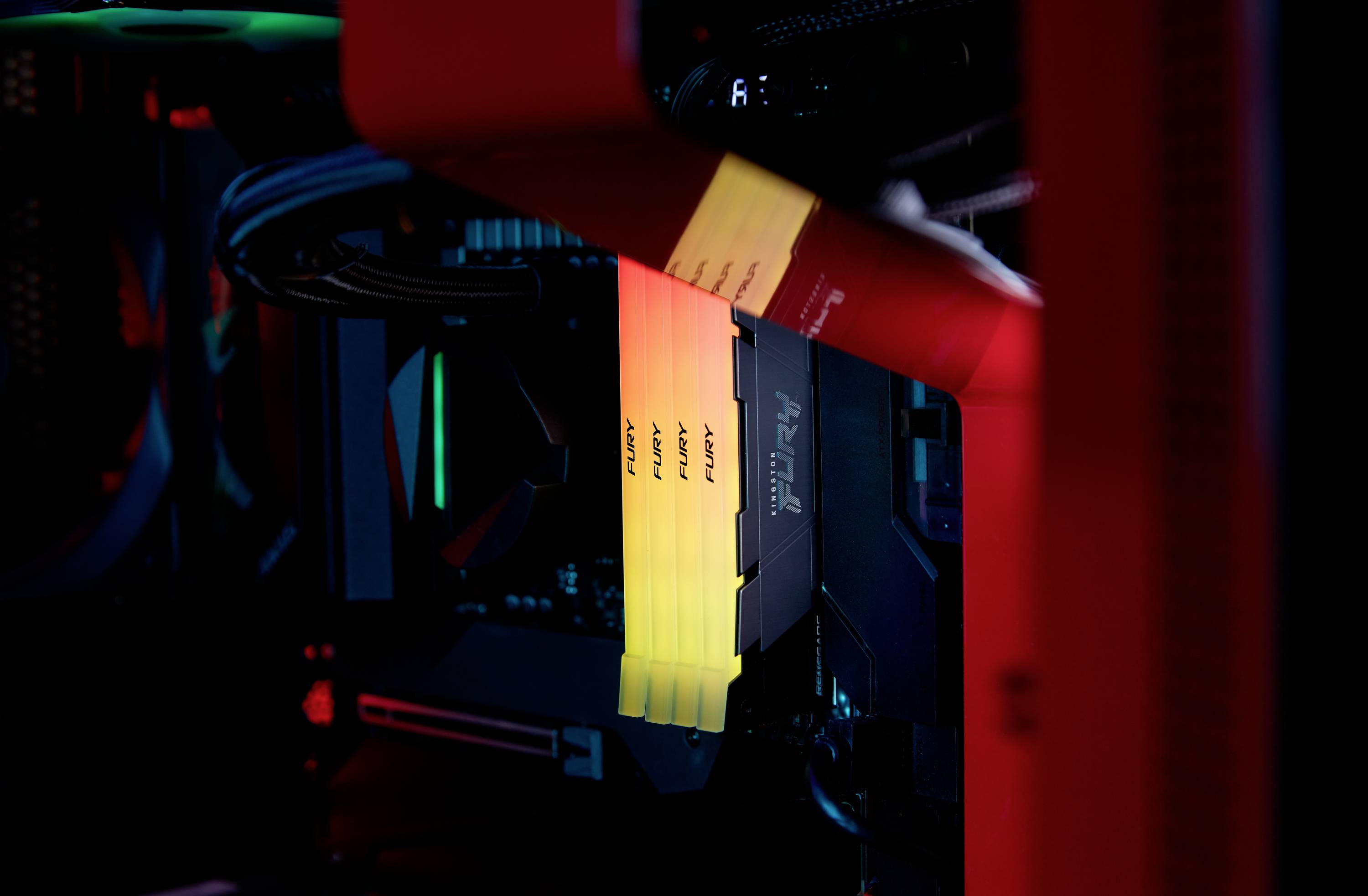 Eine Nahaufnahme eines Computergehäuses mit beleuchteten RAM-Riegeln in Gelb und Orange, eingebaut in einem Gaming-PC.
