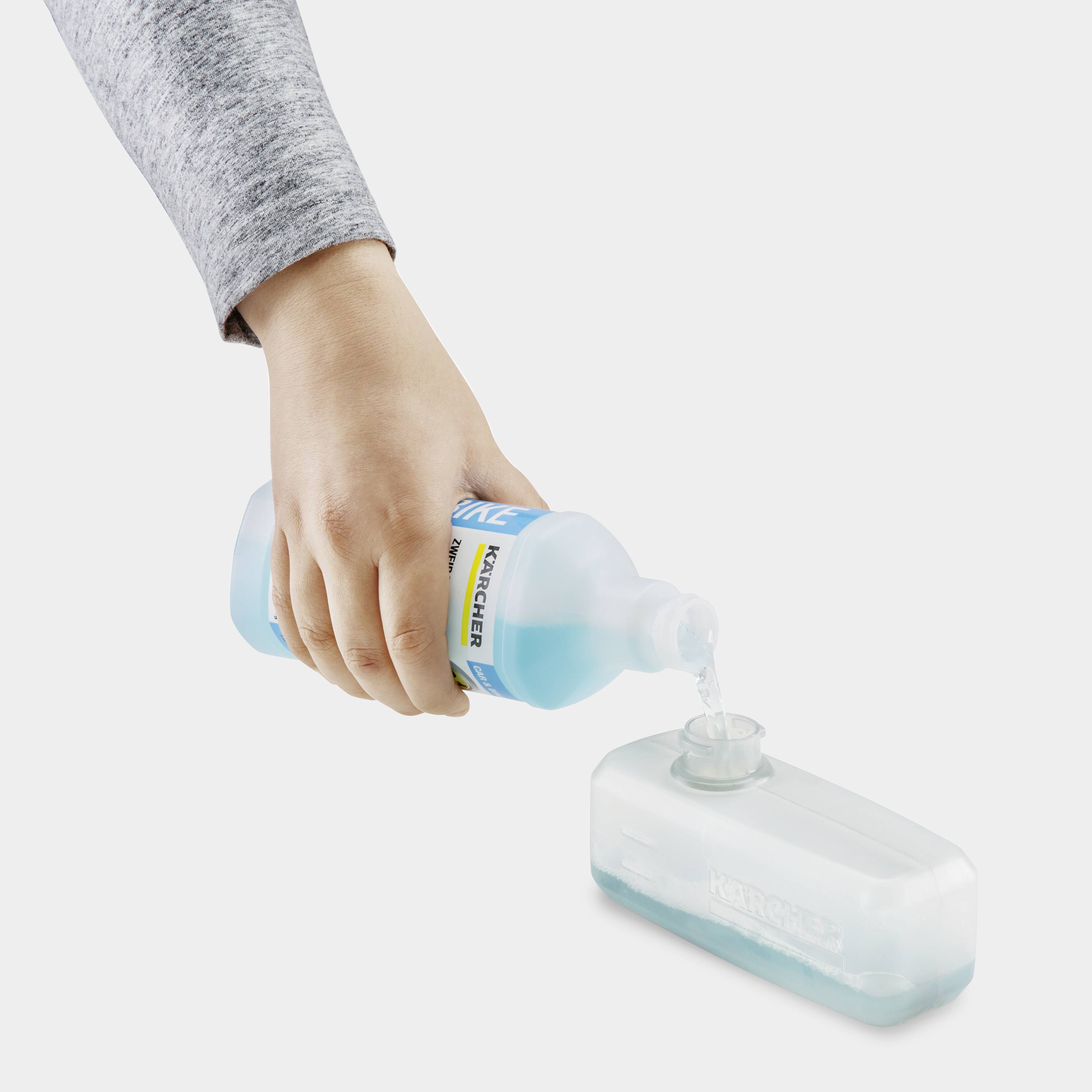 Eine Hand füllt eine Flasche mit blauer Flüssigseife.