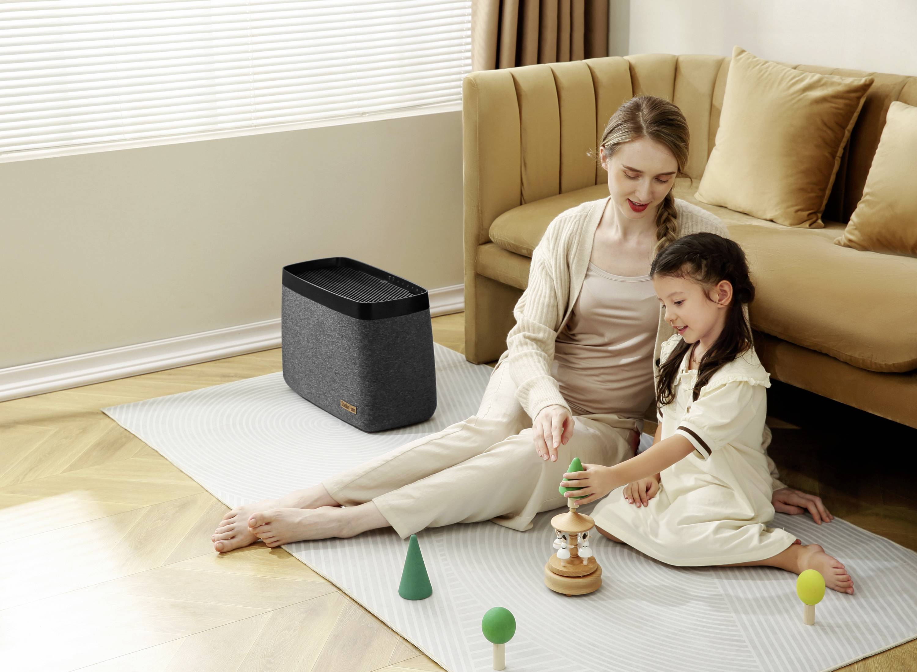 Eine Frau sitzt mit einem Kind auf einem Teppich im Wohnzimmer und spielt mit Holzspielzeug. Ein Lautsprecher steht im Hintergrund.