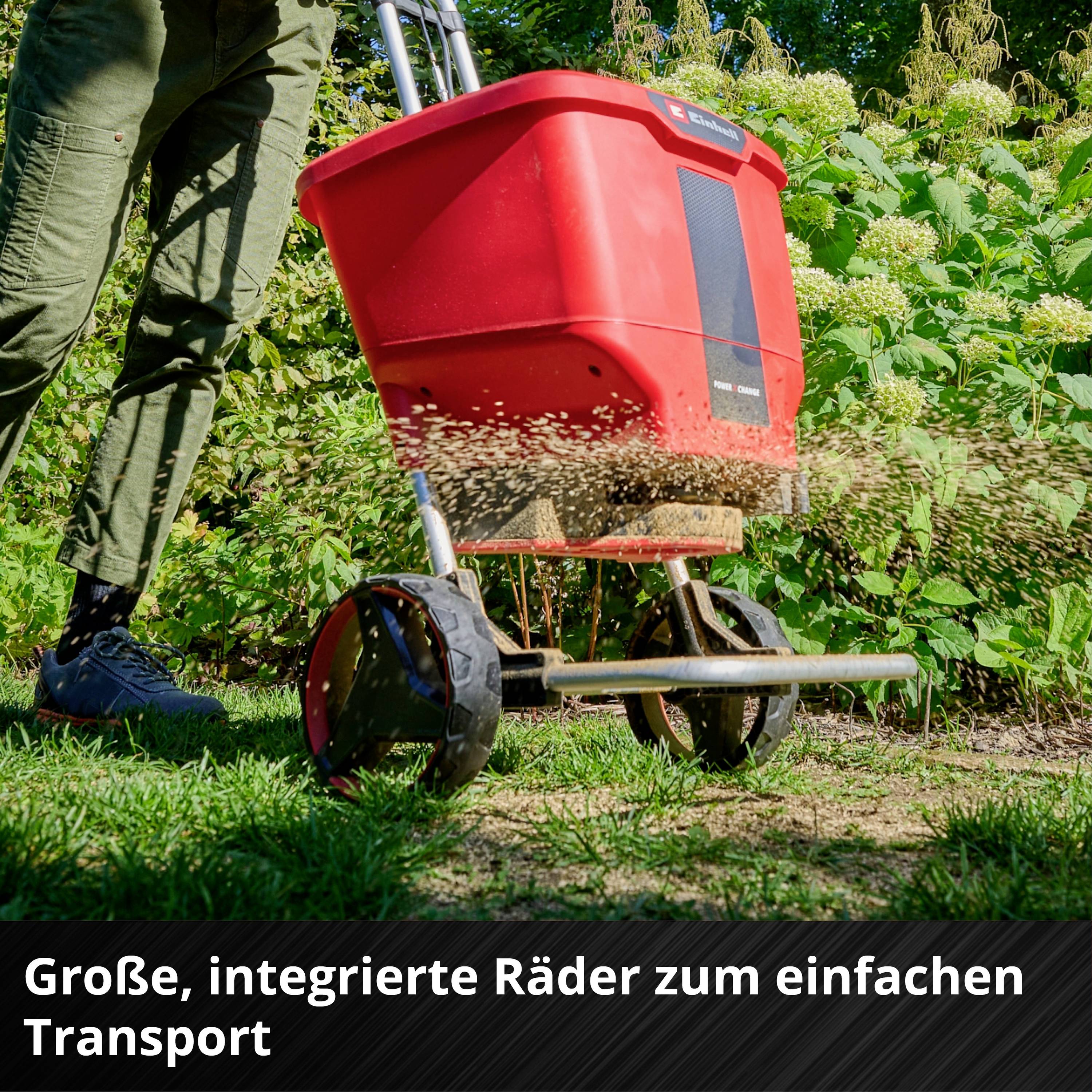 Person schiebt einen Streuwagen mit roten Behälter über Rasenfläche im Garten. Untertitel betont Bedeutung der großen Räder für leichten Transport.