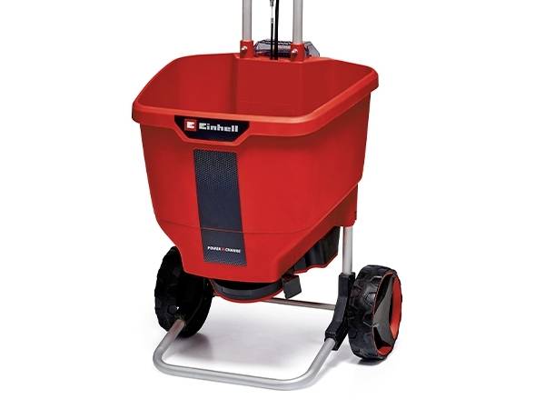 Ein roter Düngerstreuwagen mit schwarzen Rädern und silbernem Gestell.