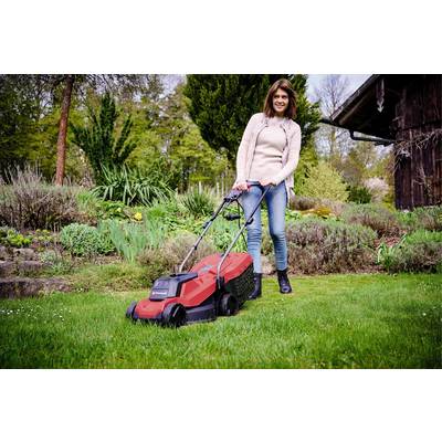 Eine Frau mäht den Rasen mit einem roten Rasenmäher in einem gepflegten Garten. Im Hintergrund sind Büsche und Bäume zu sehen.