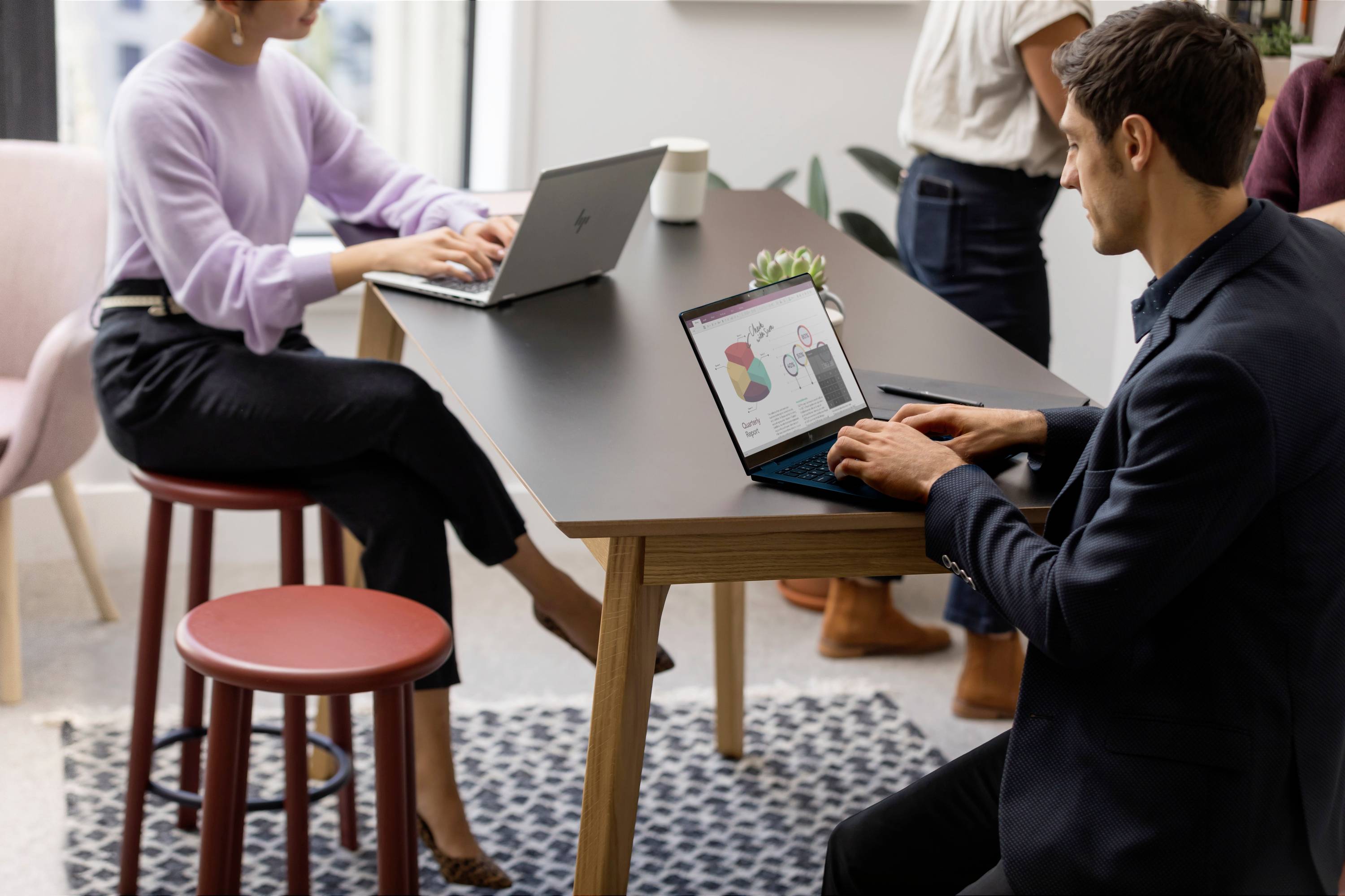 Zwei Personen arbeiten an Laptops an einem Tisch. Eine Person betrachtet ein Diagramm auf dem Bildschirm, das sich auf Datenanalyse bezieht.