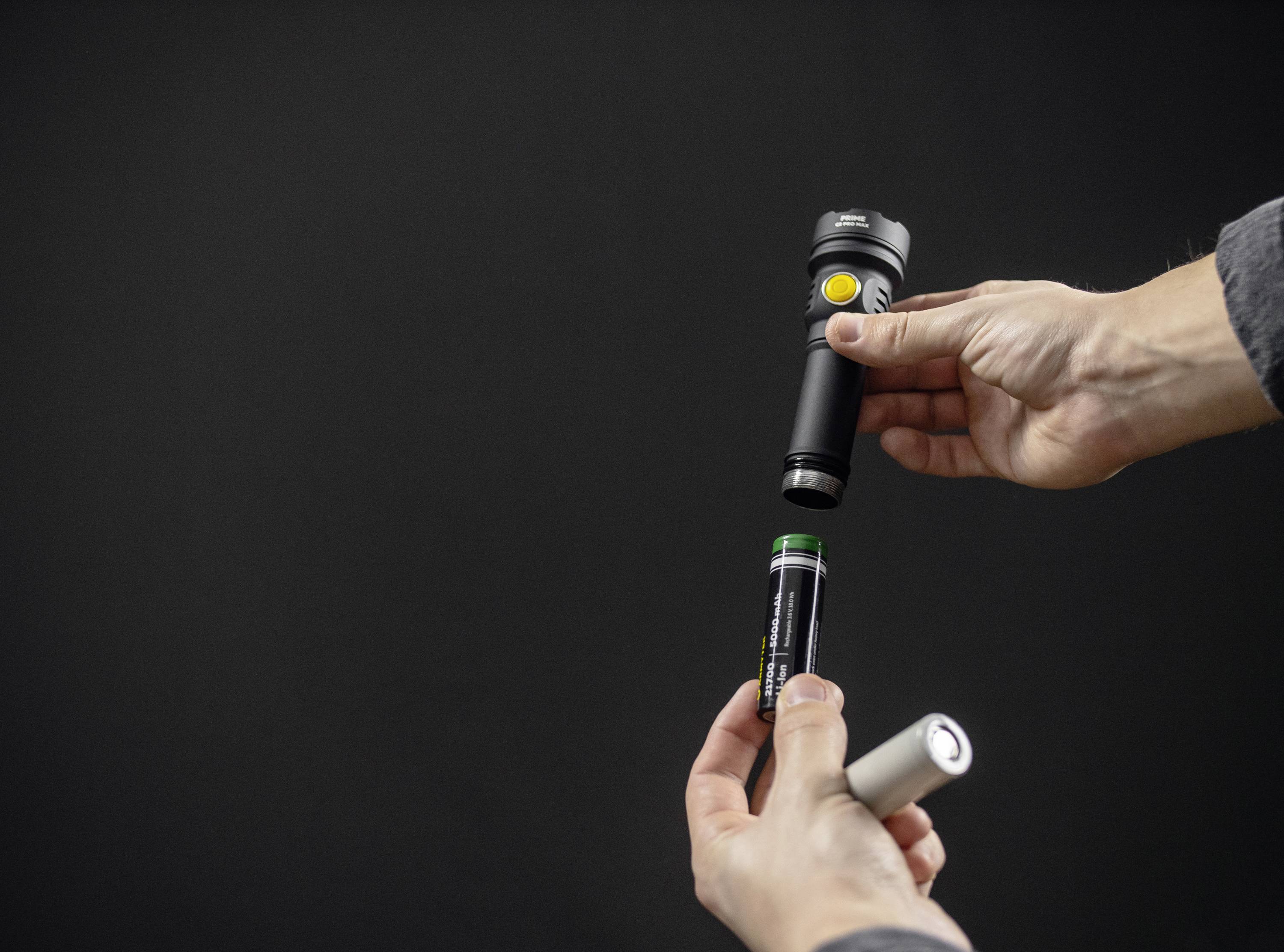 Eine Person ersetzt eine Batterie in einer Taschenlampe vor einem dunklen Hintergrund.