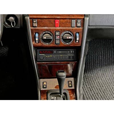 Autoradio und Klimawähler in der Mittelkonsole eines Autos mit holzgetäferten Oberflächen und Automatikgetriebeschaltung.