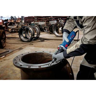 Eine Person in Schutzkleidung bearbeitet eine große Metallflansch-Verbindung mit einem Elektrowerkzeug in einer Werkhalle.