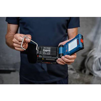 Eine Person hält eine tragbare LED-Arbeitsleuchte und eine Batterie. Die Leuchte hat ein blaues Gehäuse und viele kleine LEDs.