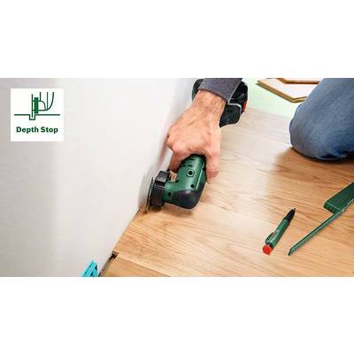'Eine Person verwendet ein Elektrowerkzeug, um einen Holzfußboden nahe der Wand zu schneiden. Auf dem Boden liegen ein Stift und ein Lineal.'