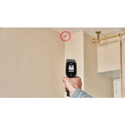 Eine Person zielt mit einem Infrarot-Thermometer auf eine Zimmerdecke. Ein roter Kreis markiert einen Punkt an der Decke.