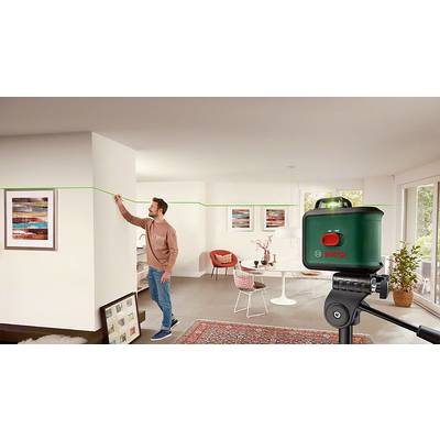 Mann richtet mithilfe eines Bosch-Lasergeräts eine grüne Linie an der Wand einer modern eingerichteten Wohnung aus.