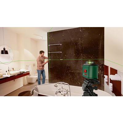 Ein Mann verwendet einen grünen Laser-Multilinienlaser in einem Badezimmer, um Fliesen an einer braunen Wand präzise auszurichten.