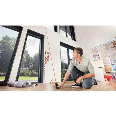 Ein Mann kniet in einem Raum und misst die Höhe eines Fensters mit einem Laser. Die gemessene Höhe beträgt 2,75 m.