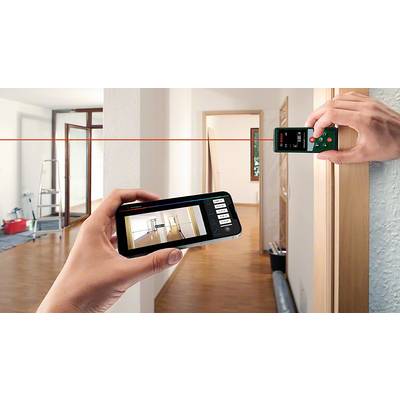 Zwei Hände halten ein digitales Laser-Messgerät und ein Smartphone mit einer App, die die Raumvermessung anzeigt. Im Hintergrund ein Raum.