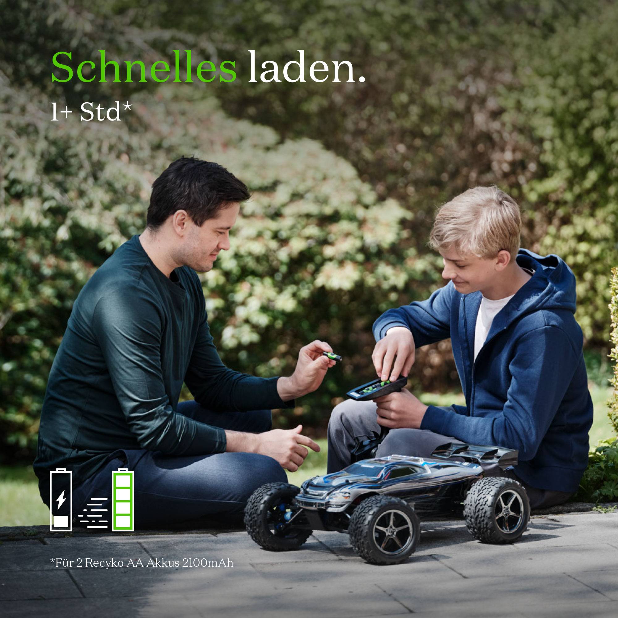 Ein Mann zeigt einem Jungen, wie man ein ferngesteuertes Auto lädt. Text oben: 'Schnelles laden, 1+ Std'.