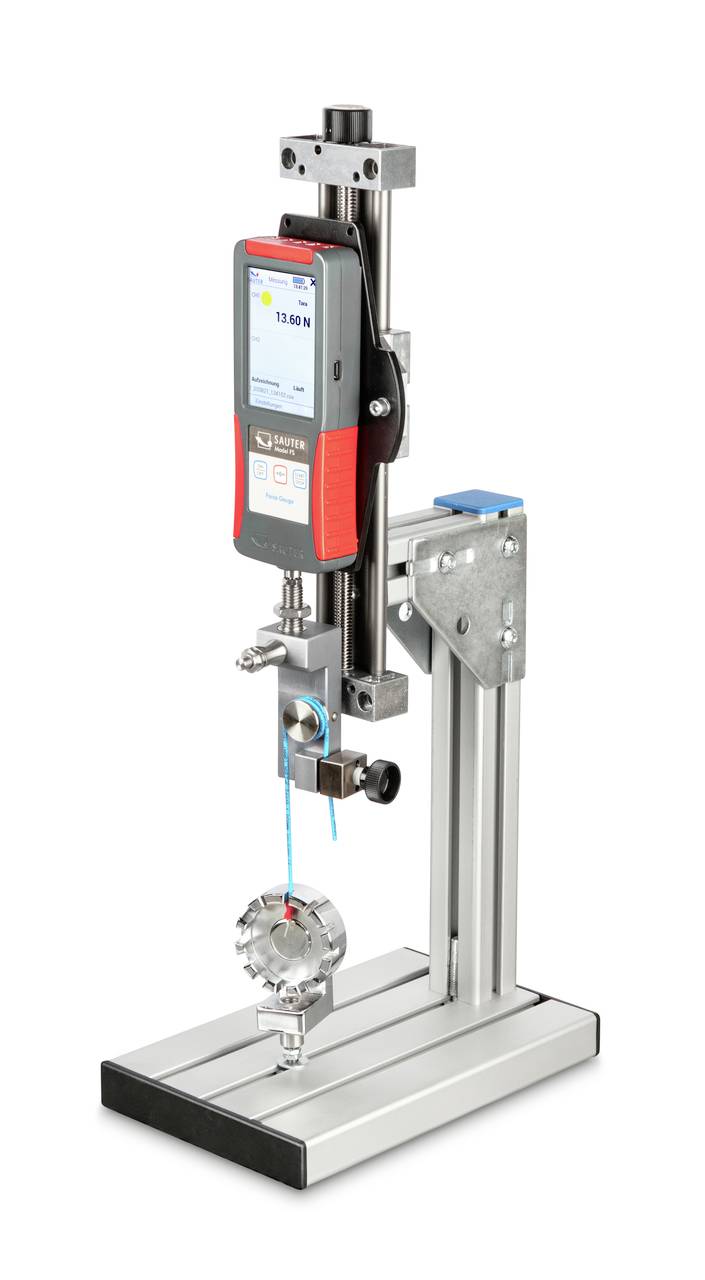 Ein Zugprüfgerät mit digitalem Display, montiert auf einem stabilen Ständer, zeigt eine Kraftmessung an. Das Gerät ist zur Materialprüfung.