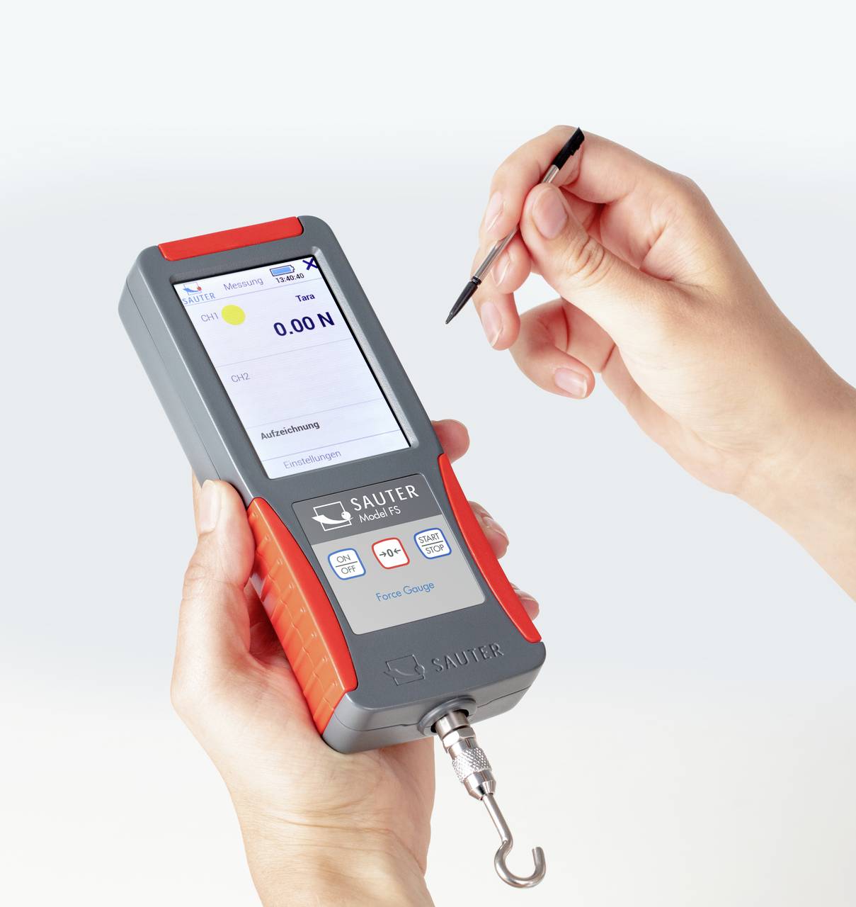 Eine Person hält ein digitales Kraftmessgerät mit Anzeige '0.00 N'. Das Gerät hat einen Haken unten und Touchscreen mit Bedienfeld.