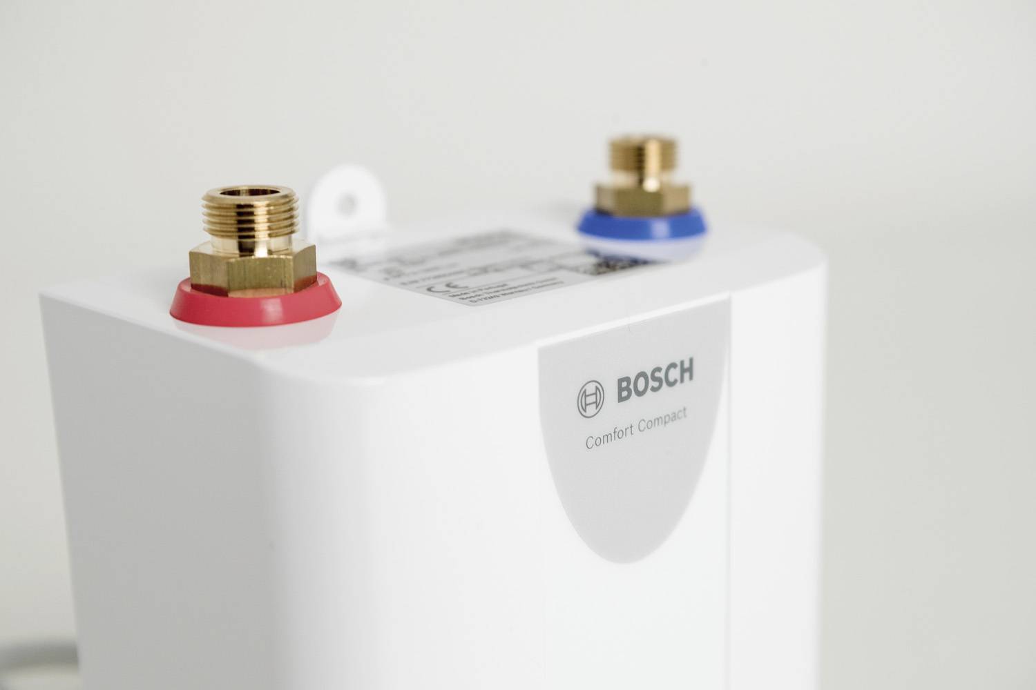 Ein weißer Wasserboiler von Bosch mit zwei farbigen Anschlüssen (rot und blau) auf der Oberseite, geeignet für Warmwasserbereitung.