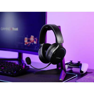 Ein Gaming-Headset mit Mikrofon steht auf einem Schreibtisch neben einem Monitor und einer Spielkonsole; alles in violetten Licht getaucht.