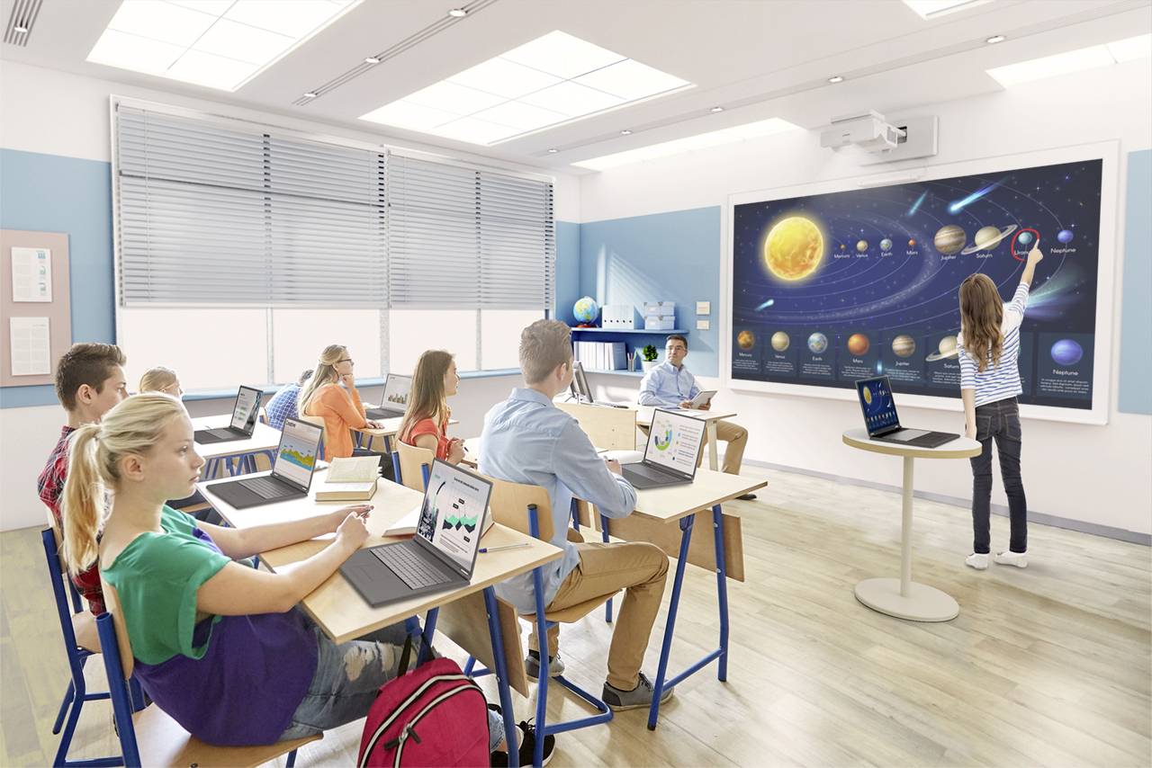 Schüler im Klassenzimmer lernen über das Sonnensystem. Eine Schülerin zeigt auf ein interaktives Display mit Planetenbildern.