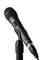 Schwarzes Mikrofon auf Ständer, leicht nach vorne geneigt, vor neutralem Hintergrund.