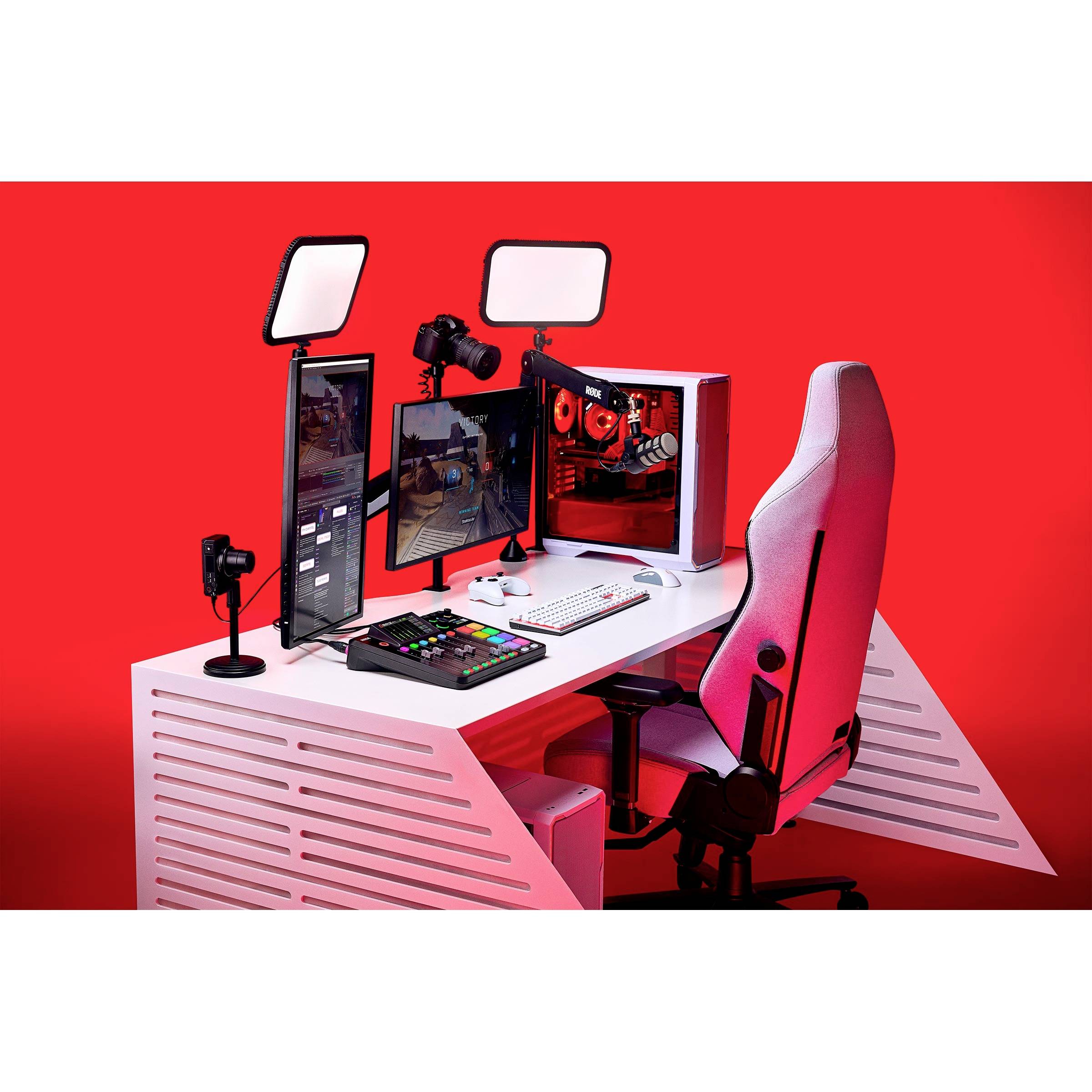 'Ein moderner Gaming-Schreibtisch mit rot beleuchtetem PC, zwei Monitoren, Gaming-Tastatur und -Maus, sowie einem ergonomischen Stuhl.'