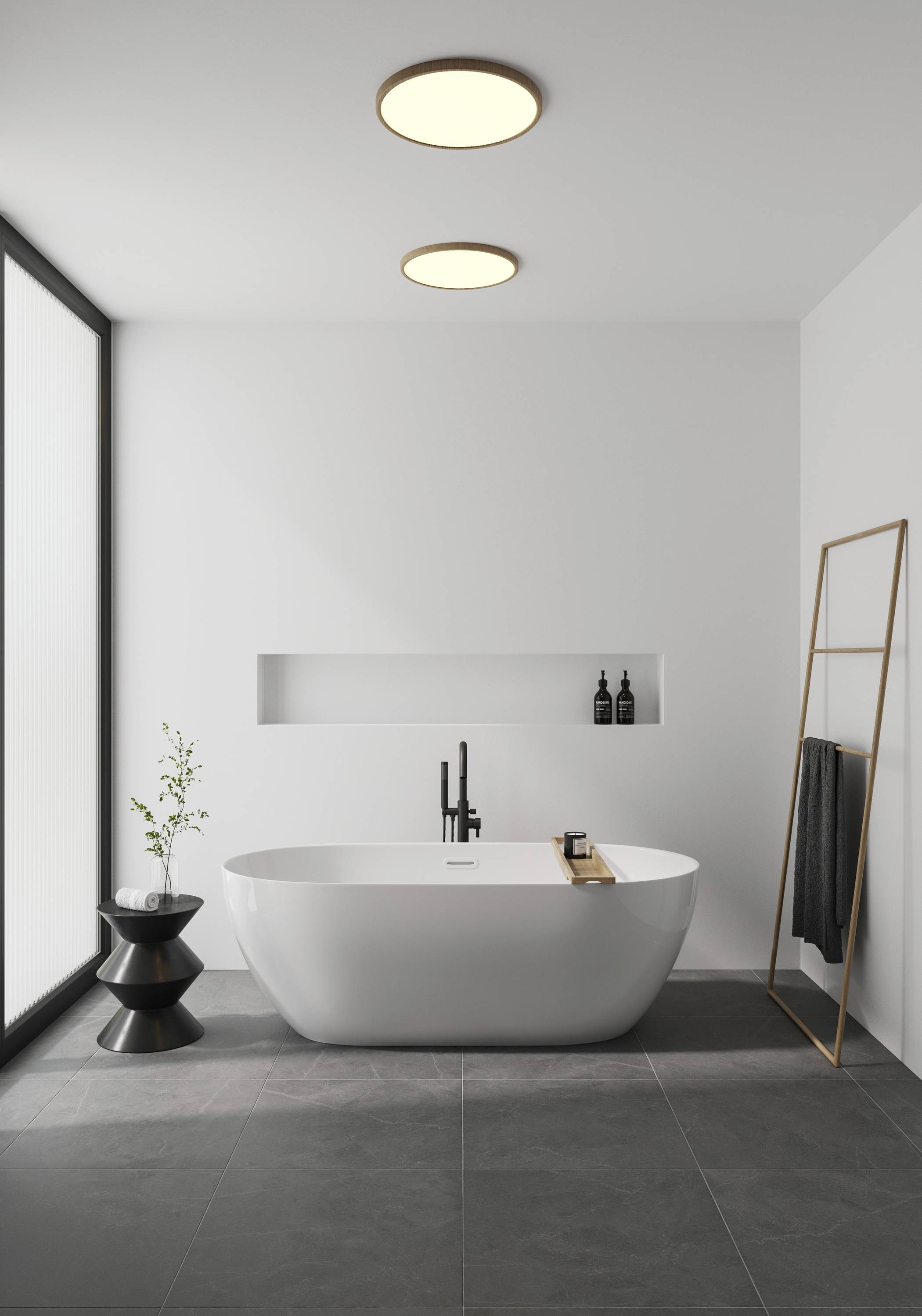 Ein modernes, minimalistisches Badezimmer mit freistehender Badewanne, schwarzem Wasserhahn und Regal. Zwei Lichter an der Decke.