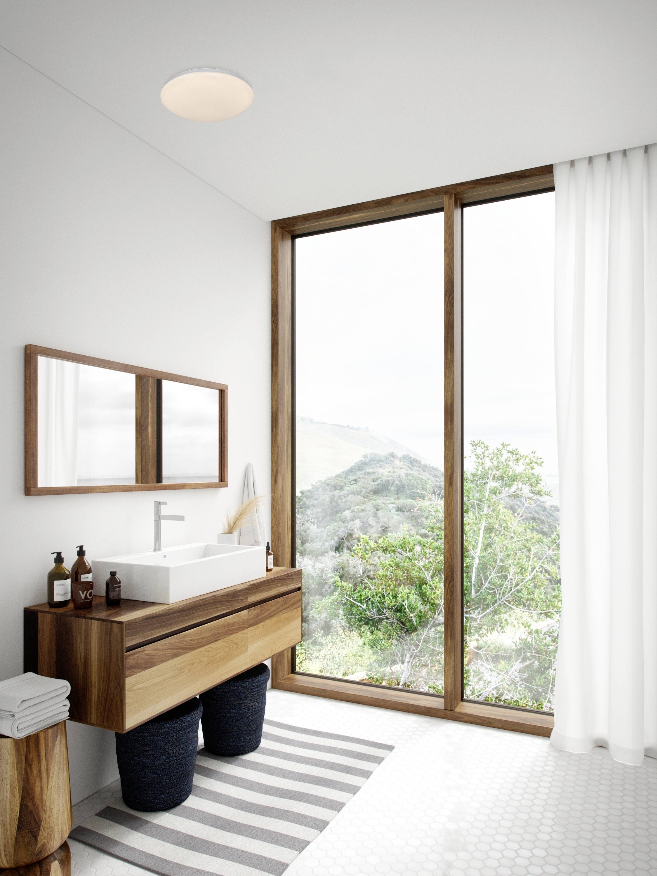 Helles Badezimmer mit Waschbecken aus Holz, großem Fenster mit Blick auf Landschaft und modernen Accessoires.