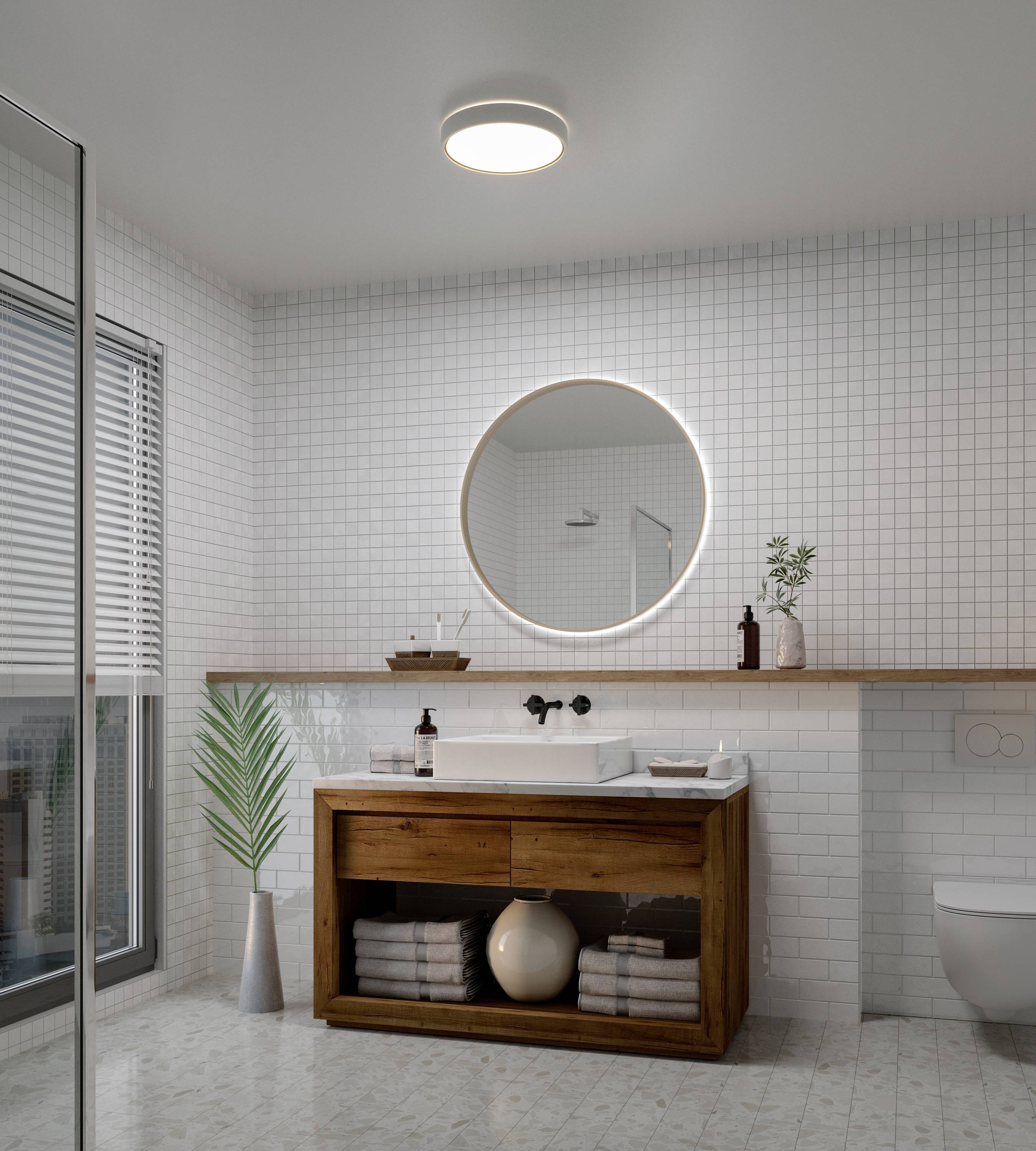 Modernes Badezimmer mit weiß gefliesten Wänden, einem runden Spiegel über einem Holzwaschtisch und Glasdusche links.