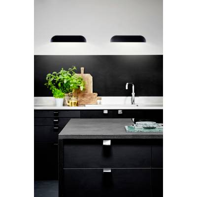 Moderne Küche mit schwarzen Schränken, Edelstahlspüle, Schneidebrettern und frischen Kräutern auf der Arbeitsplatte.