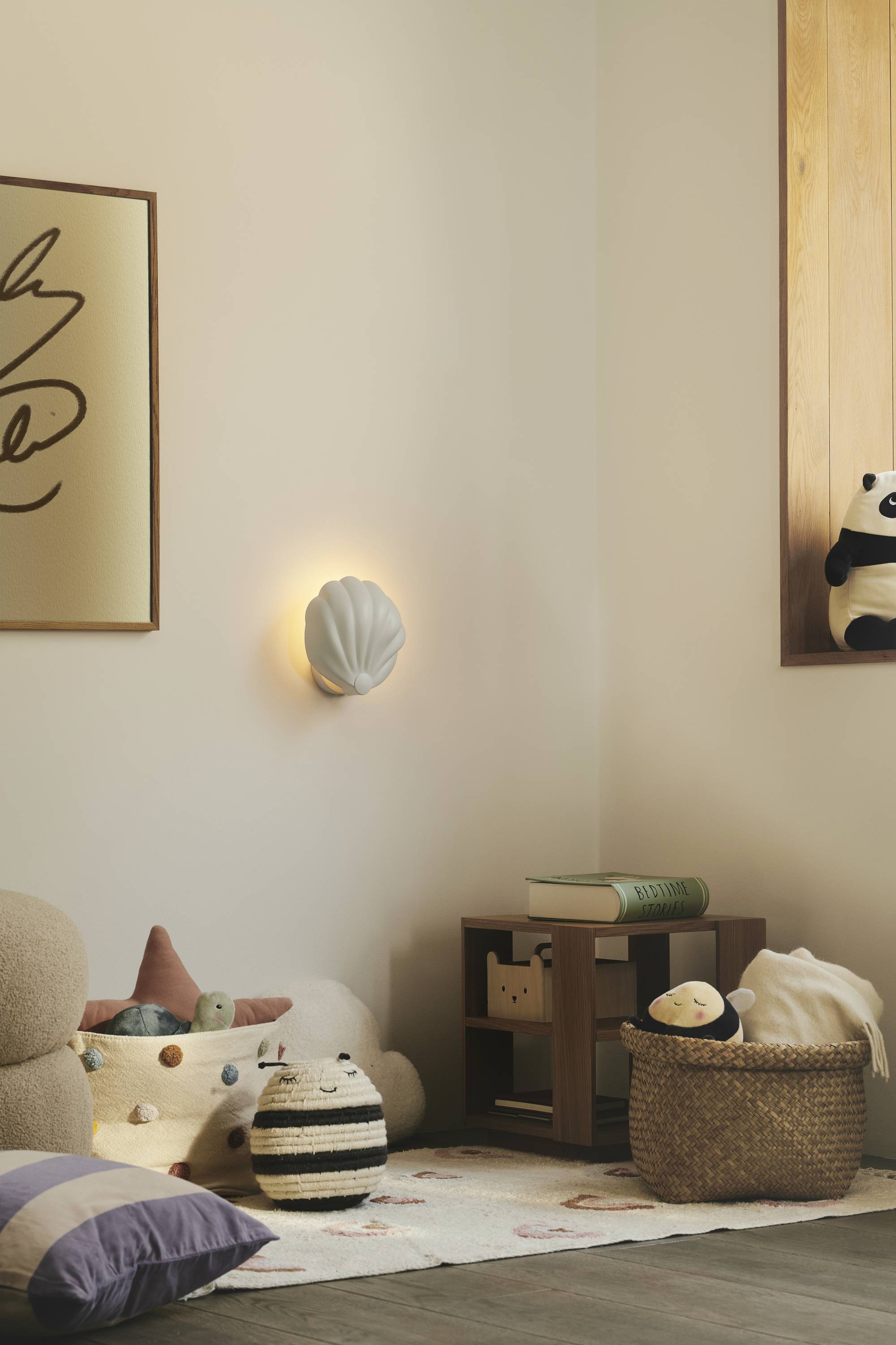 Gemütliches Kinderzimmer mit kuscheligen Plüschtieren, warmem Licht und Holzdetails. Ein Wandbild und ein Korb mit Spielzeug ergänzen die Szene.