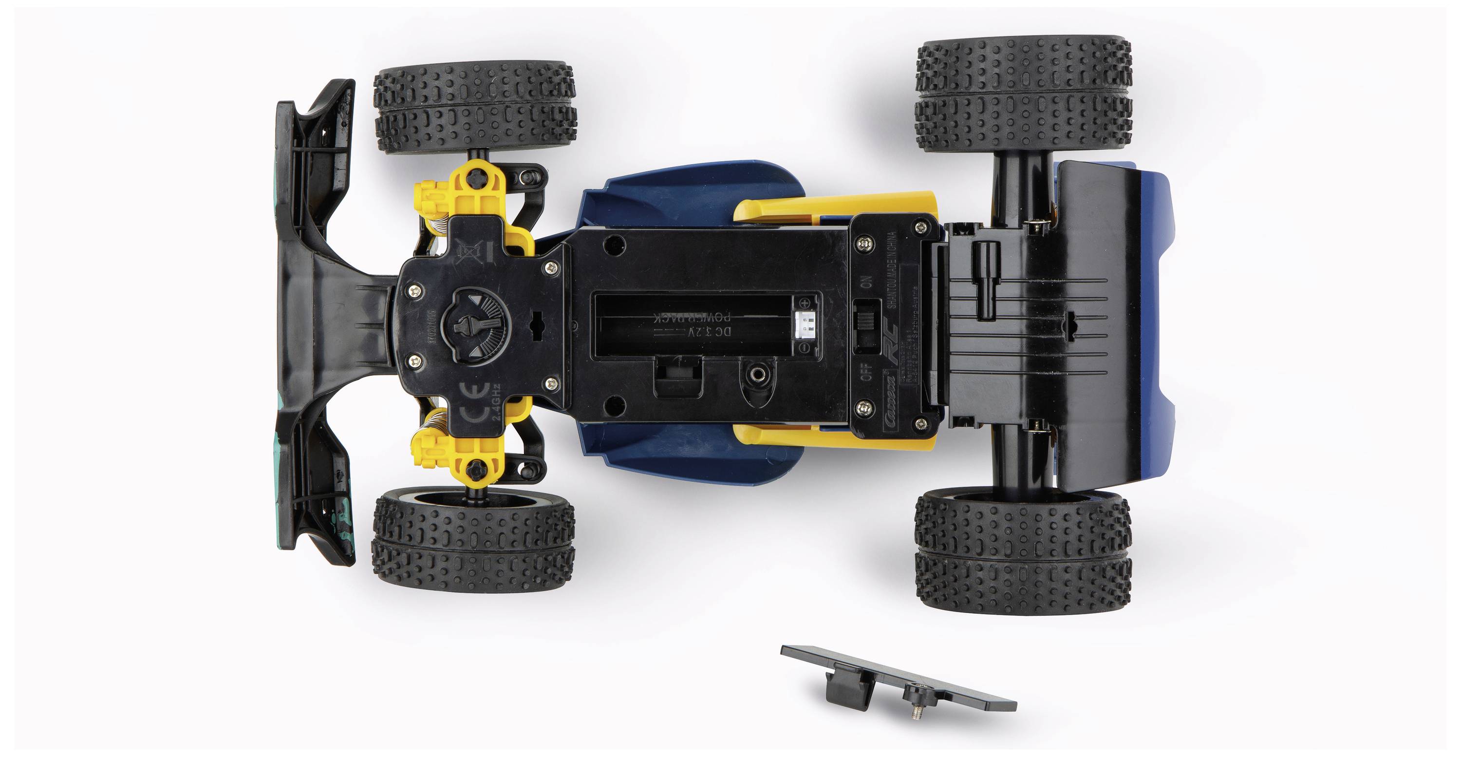 Spielzeugauto auf dem Kopf liegend mit abgenommenem Batteriefachdeckel, zeigt Innenmechanik und Struktur des Fahrzeugs.
