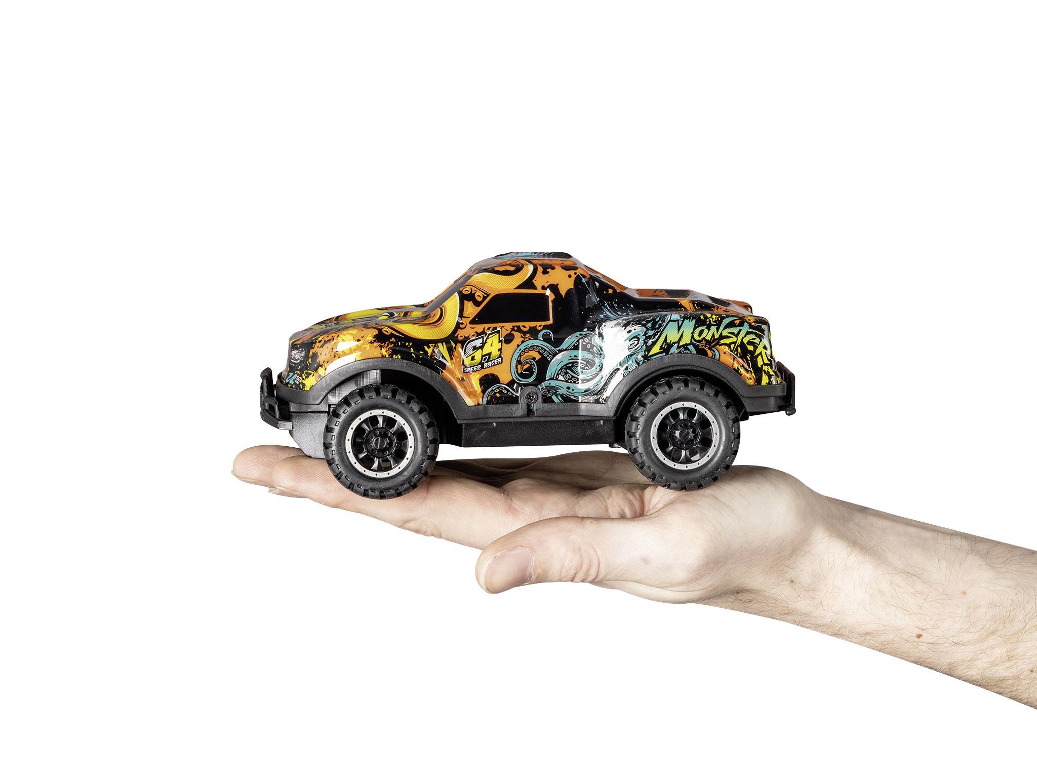 Eine menschliche Hand hält ein kleines Spielzeugauto in der Farbe Orange mit grünen Mustern; Hintergrund ist weiß.