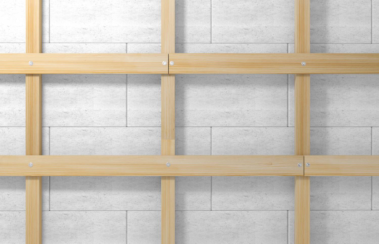 Holzrahmen an grauer Betonwand befestigt, symmetrisch mit sichtbaren Schraubverbindungen. Quadratische Felder bilden gleichmäßiges Muster.