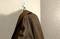 Eine braune Jacke hängt an einem Haken an der Wand. Die Wand hat eine strukturierte Oberfläche.