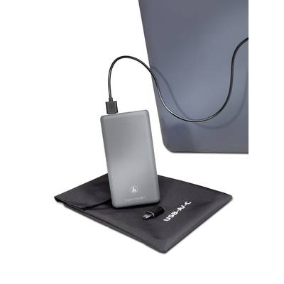 Eine silberne Powerbank ist über ein Kabel mit einem Laptop verbunden. Unter der Powerbank liegt eine schwarze Tasche mit der Aufschrift 'USB-C'.